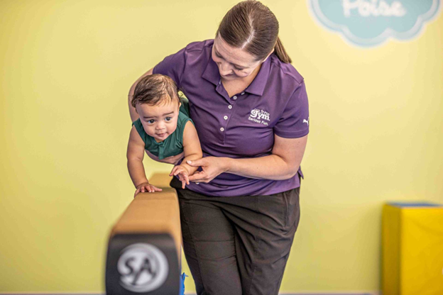 The little gym instructor is teaching a little child 