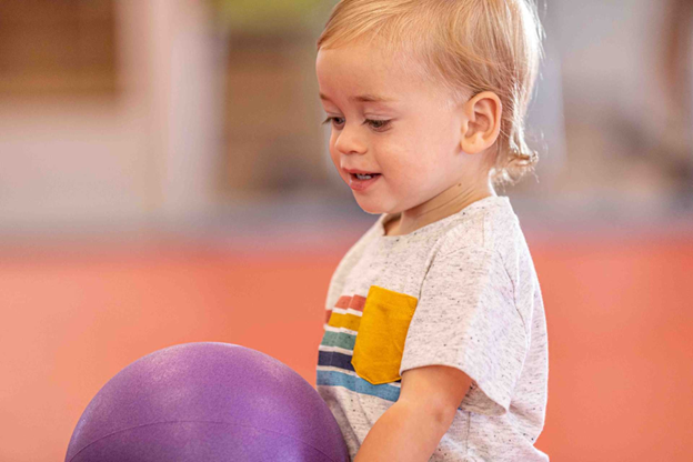 infant boy sitting with a purple ball