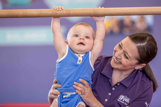 a little gym instructor supporting an infant boy