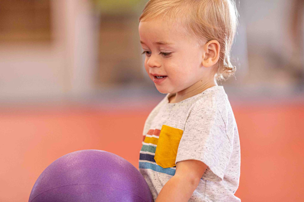 A young child playing with ball at the little jym