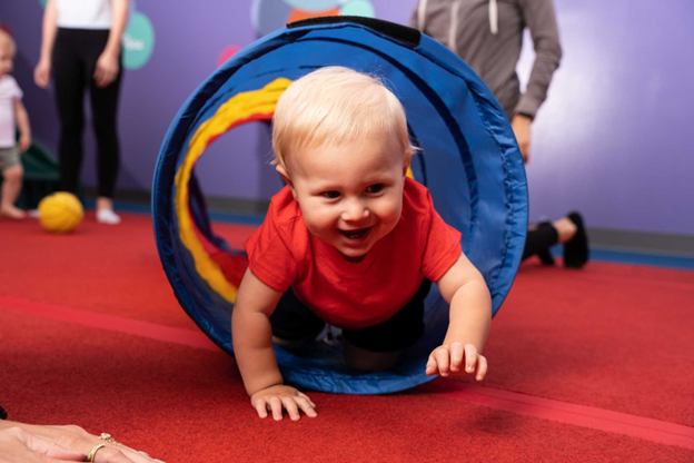 infant boy crawling with a material tunnel