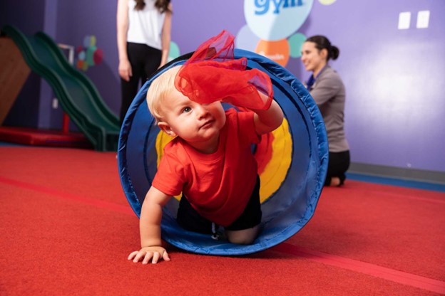 young boy crawling through a material tunnel